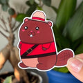 Cartoon beaver sticker held in front of potted plants