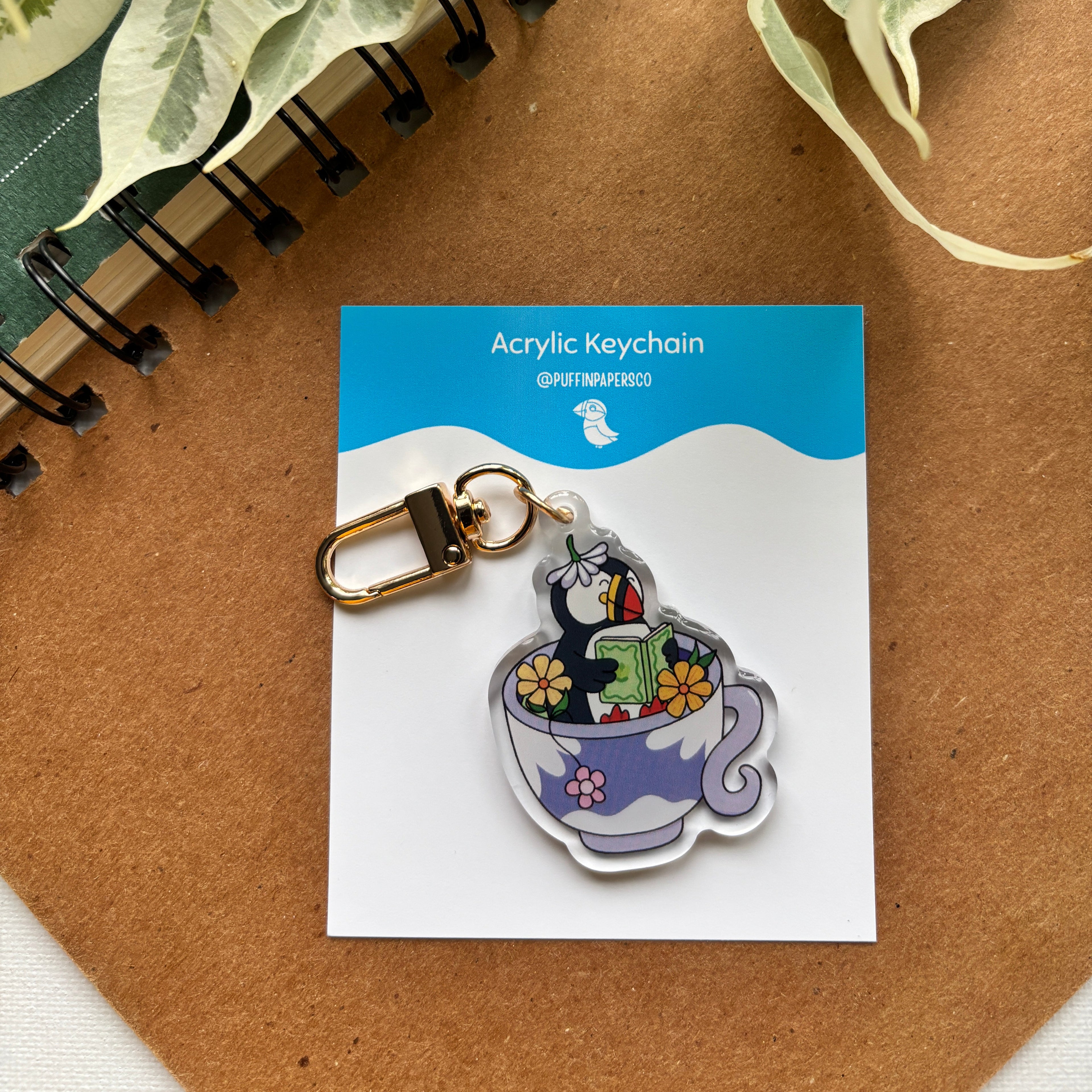 Acrylic keychain on a card with a notebook and leaves in the background