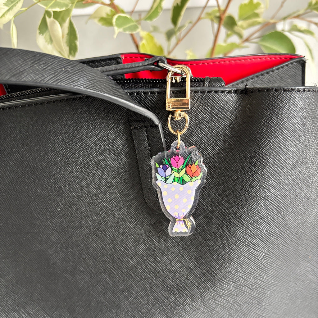Floral charm attached to a black bag with a red interior.